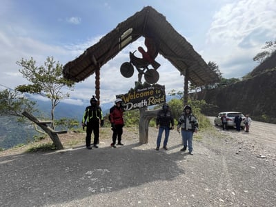 Adventure motorcycle riders near welcome to death road sign